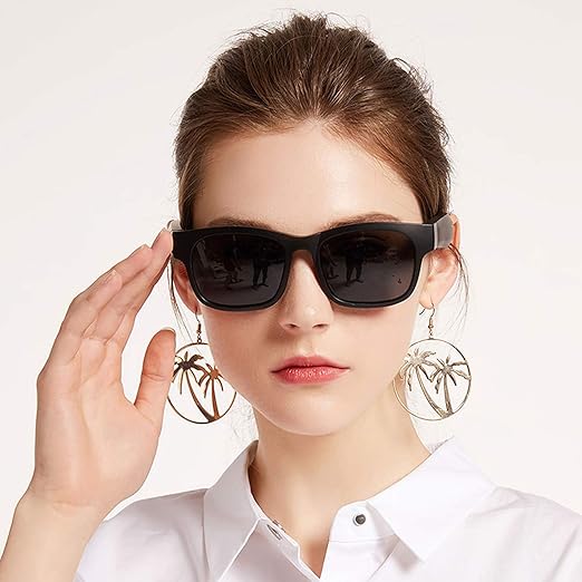 Woman wearing AUGLASS audio glasses with blue light lenses and acetate frame, touching her stylish black sunglasses.